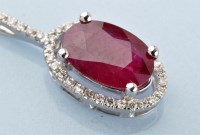 Lot 909 - A ruby and diamond cluster pendant, the oval...