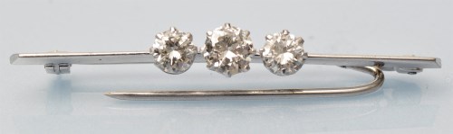Lot 932 - A three stone diamond bar brooch, the...