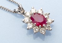 Lot 950 - A ruby and diamond cluster pendant, the oval...