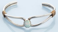 Lot 1003 - An opal and silver bangle, the oval opal...