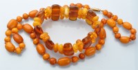 Lot 1032 - An egg yolk amber necklace, the graduated oval...