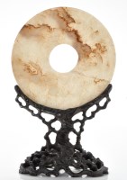 Lot 586 - Russet veined pale celadon jade disc, bi, with...