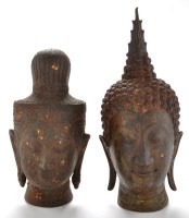 Lot 672 - Two South-East Asian bronzed metal deity heads,...