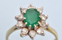 Lot 1208 - An emerald and diamond cluster ring, the oval...