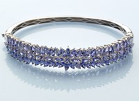 Lot 605 - A tanzanite bangle, the top half set with...