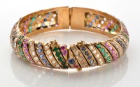 Lot 776 - A gemstone set bangle, the yellow metal bangle...