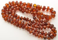Lot 814 - A long amber bead necklace of cylindrical and...