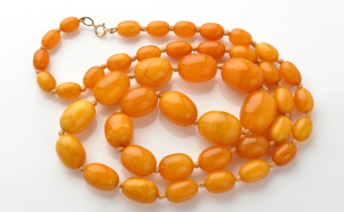 Lot 920 - An amber bead necklace, the oval beads strung...