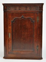 Lot 1145 - A late George III oak hanging corner cupboard,...