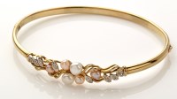 Lot 775 - A 9ct. yellow gold pearl and diamond bangle,...