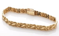 Lot 872 - A yellow metal bark pattern bracelet, the...