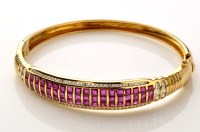 Lot 834 - A ruby, diamond and yellow metal bangle, set...