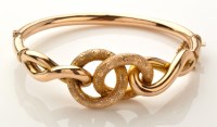 Lot 892 - A 9ct. knot pattern bangle, hollow cast, the...