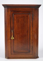 Lot 1226 - A Georgian oak hanging corner cupboard with a...