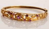 Lot 906 - A ruby and 9ct. gold bangle, the upper section...