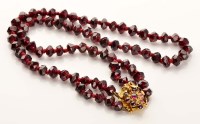 Lot 918 - A garnet and gold necklace, the faceted garnet...