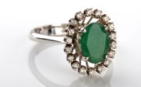 Lot 1102 - An emerald and diamond ring, the oval mixed...