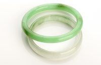 Lot 765 - Two green stone bangles, of plain polished...