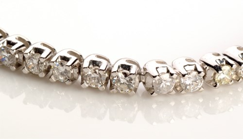 Lot 874 - A diamond tennis bracelet, set with fifty-two...