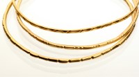 Lot 742 - Three Egyptian gold bangles, bearing hallmarks...