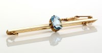 Lot 808 - An aquamarine bar brooch, the central emerald...