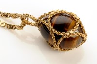 Lot 858 - A modern tigers eye and yellow metal pendant,...