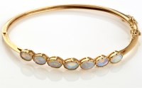 Lot 830 - An opal and 9ct. yellow gold bangle, the seven...