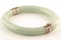 Lot 814 - A green stone bangle, with white metal mounts...