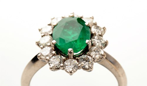 Lot 840 - An emerald and diamond cluster ring, the...