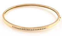 Lot 881 - A diamond set yellow metal bangle, channel set...