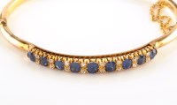 Lot 891 - A sapphire and diamond set yellow metal bangle,...