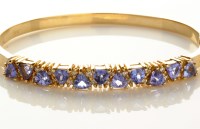 Lot 936 - A tanzanite and diamond bangle, the front set...