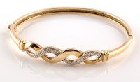 Lot 982 - A 9ct. yellow gold and diamond set bangle, the...