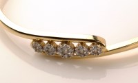 Lot 993 - A diamond and yellow metal bangle, the front...