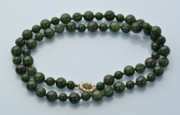 Lot 853 - A single row nephrite bead necklace, strung...