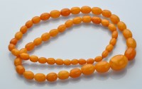 Lot 857 - A single row graduated amber bead necklace,...