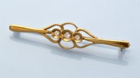 Lot 870 - A diamond set 18ct. yellow bar brooch, the...