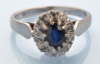 Lot 874 - A sapphire and diamond cluster ring, on white...