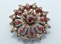 Lot 897 - A diamond and ruby circular brooch of floral...