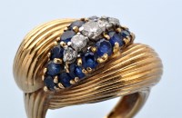 Lot 911 - A sapphire and diamond dress ring, the line of...