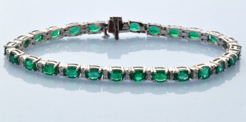 Lot 950 - An emerald and diamond line bracelet, the...