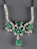 Lot 879 - A diamond and emerald necklace, the oval...