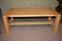 Lot 610 - A light wood coffee table with glass undertier,...