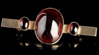 Lot 977 - A garnet bar brooch, the three graduated oval...