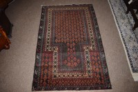 Lot 900 - An old Baluchi prayer rug in shades of red and...