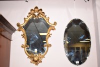 Lot 916 - A modern shaped wall mirror in ornate gold...