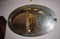 Lot 950 - An oval bevelled mirror in hammered pewter...