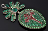 Lot 555 - A green and red paste pendant, the bow and...