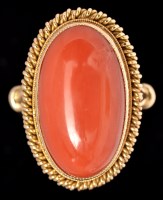 Lot 585 - A coral dress ring, the oval coral cabochon...