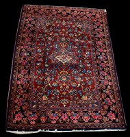 Lot 646 - A Kashan rug, the floral design on rust-red...